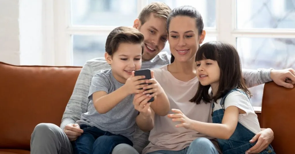 Familj som använder mobiltelefon tillsammans i hemmet