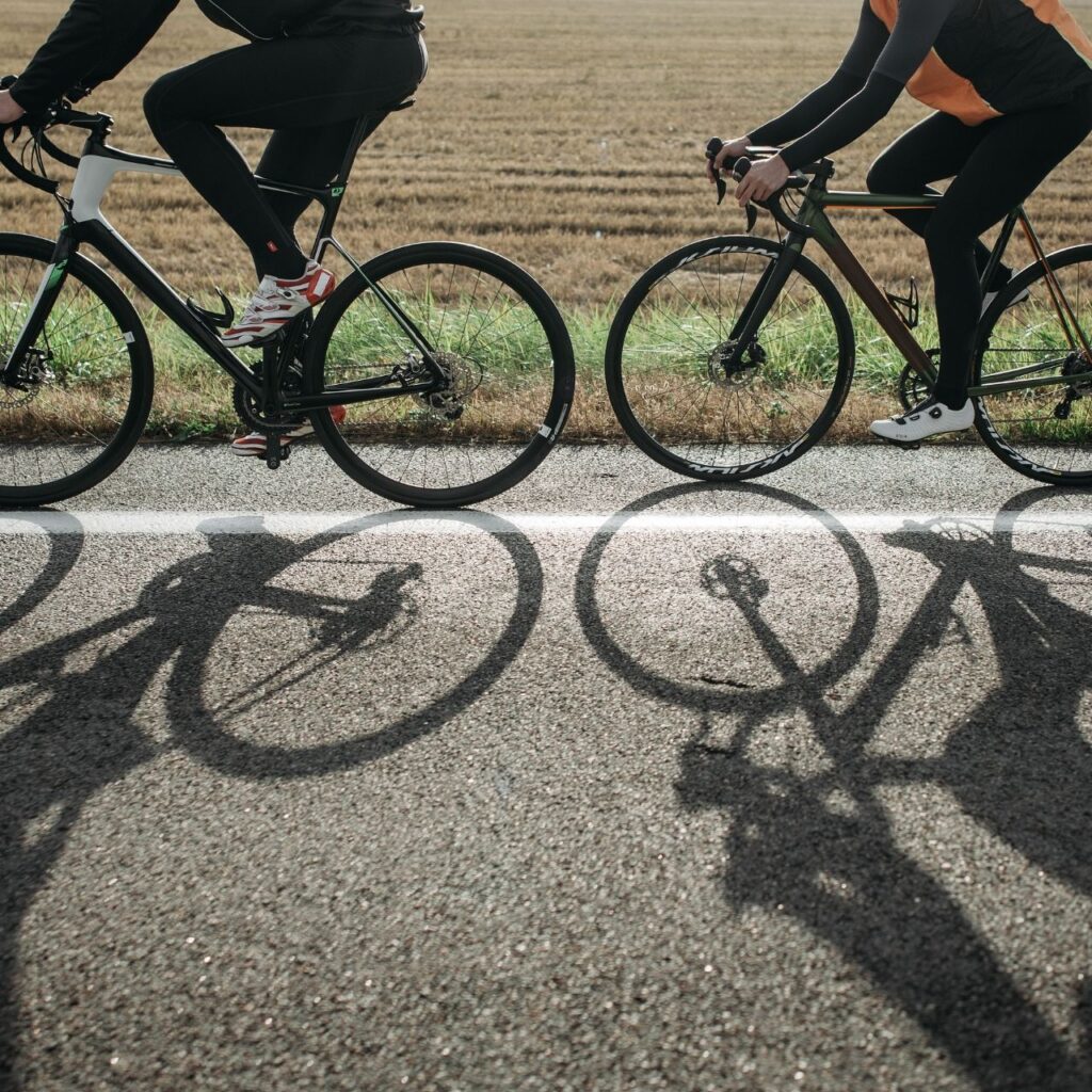 Två cyklister i tävlingsmoment, pedalerna snurrar snabbt i en kraftfull hastighet