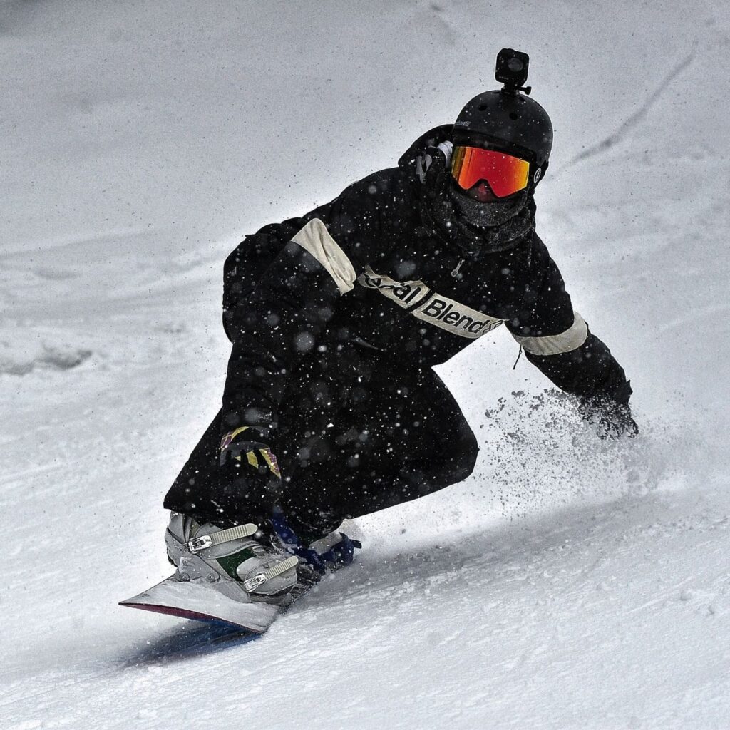 Svartklädd snowboardåkare glider elegant nerför backen