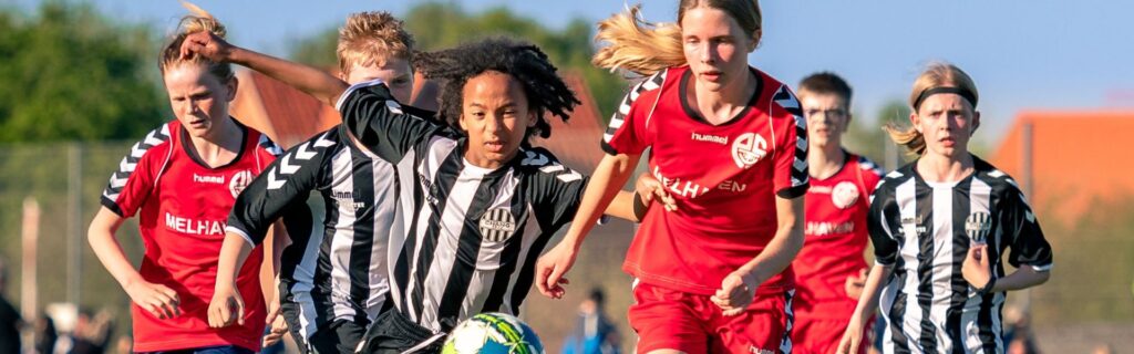 Mixat Fotbollslag: En grupp fotbollsspelare från olika bakgrunder spelar fotboll på planen