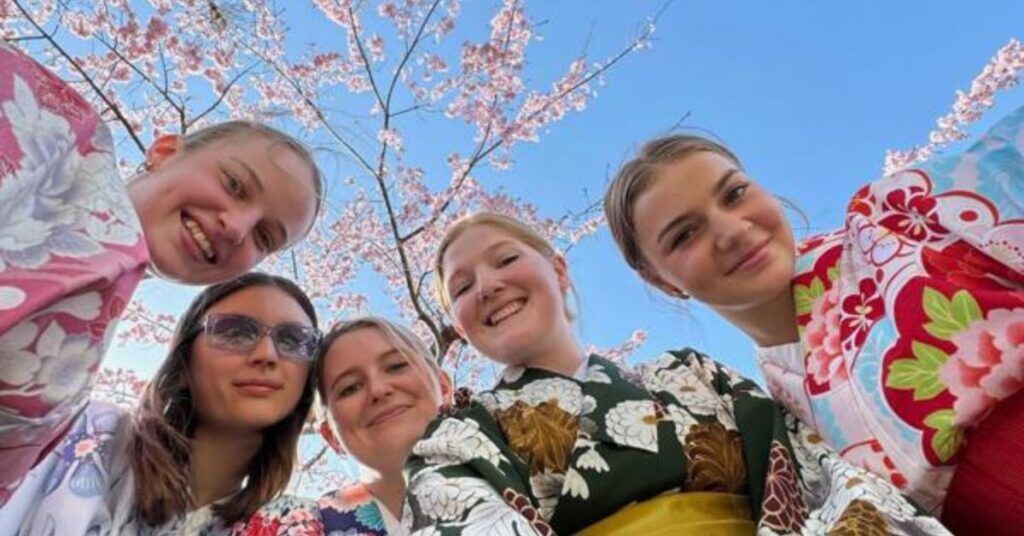 Ungdomsgrupp i kimono under körsbärsblommor på en Kilroy-inspirerad gruppresa i Japan