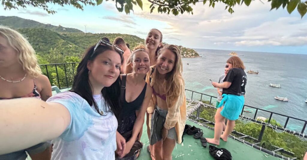 Ungdomsgrupp på utsiktsplats vid havet under en gruppresa i Asien med fokus på äventyr och gemenskap